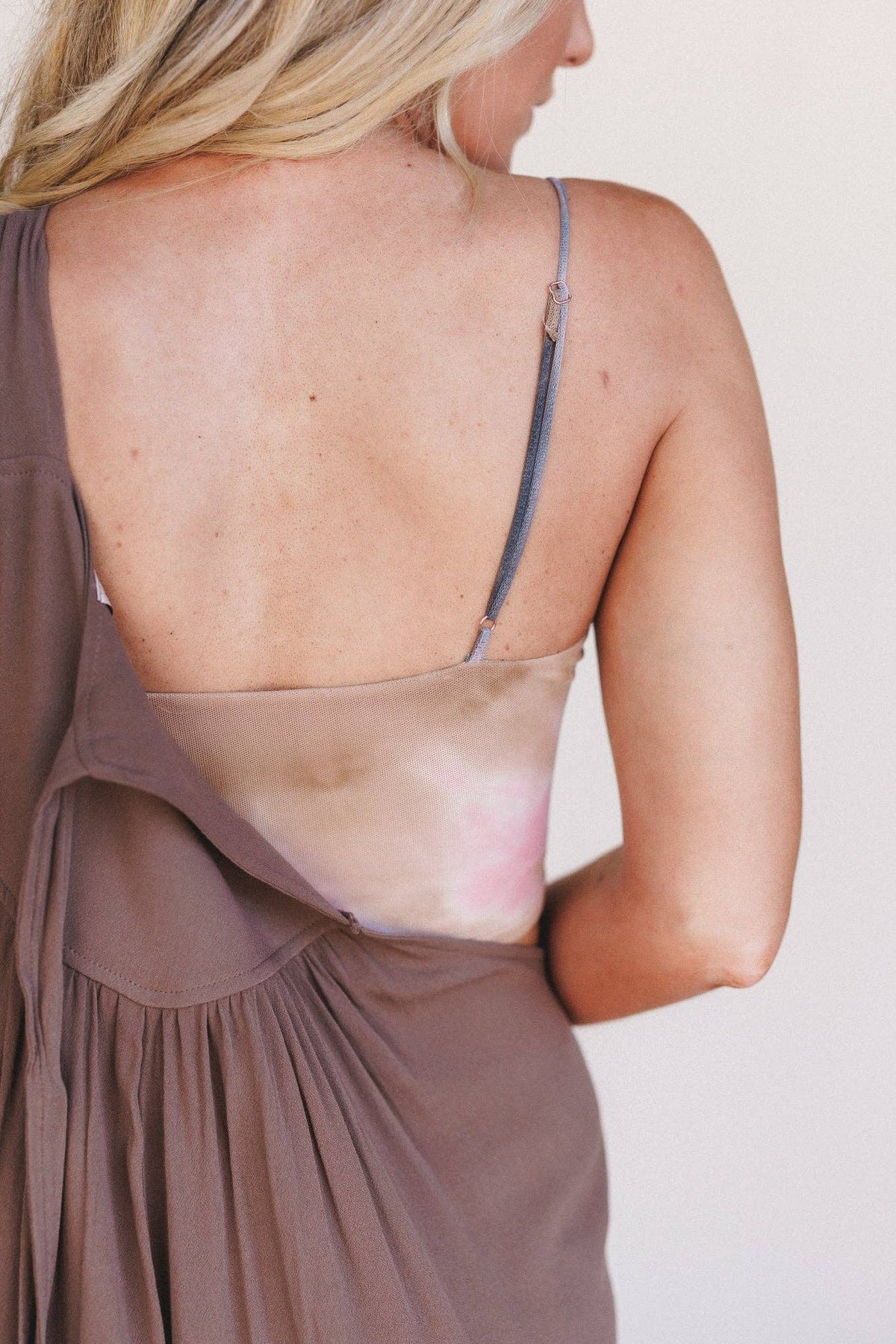Woman wearing a brown dress with a sheer overlay on a plain background