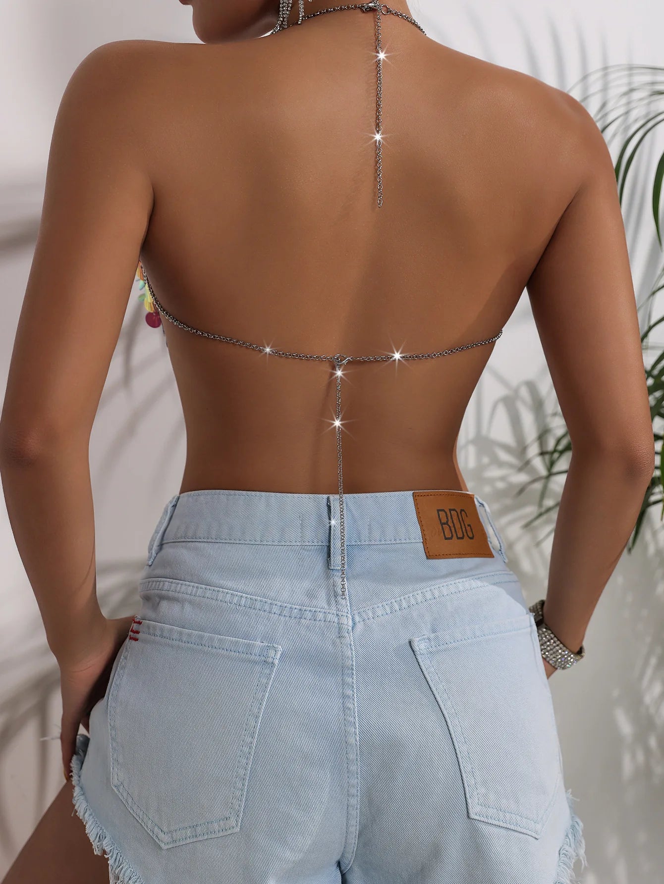 Y2K-inspired, backless festival look with prismatic high-refraction crystal chain, high-rise denim shorts