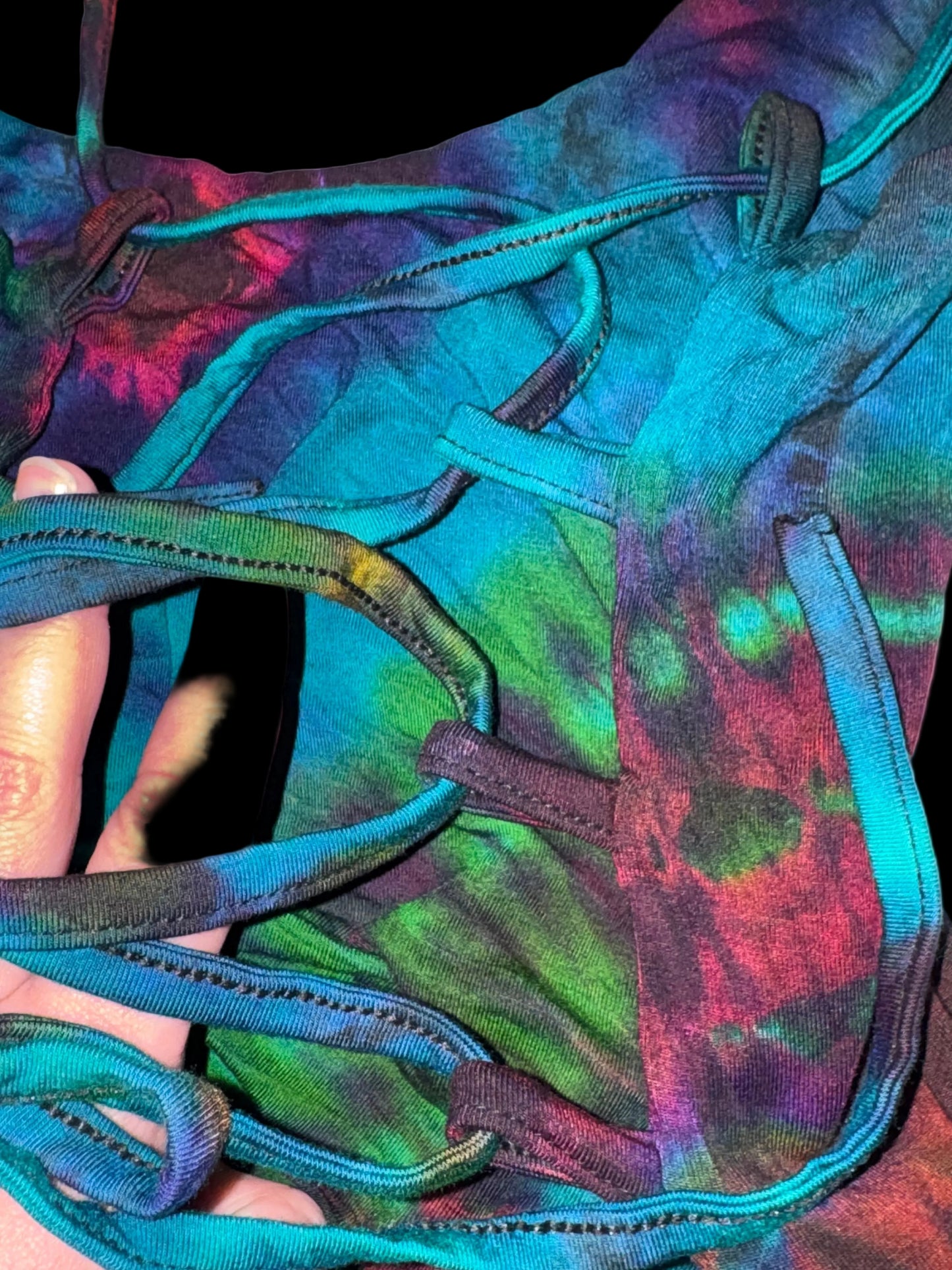 Colorful tie-dye swimsuit with a close-up of a hand holding it.