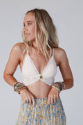 Woman wearing a white lace top and patterned skirt with a plain background